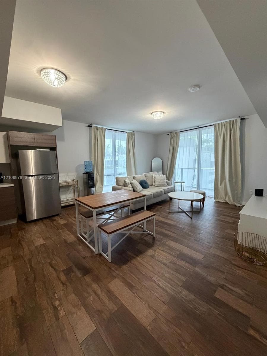 Contemporary kitchen featuring dual-tone cabinetry, stainless steel appliances, solid surface countertops, and wood-finish flooring