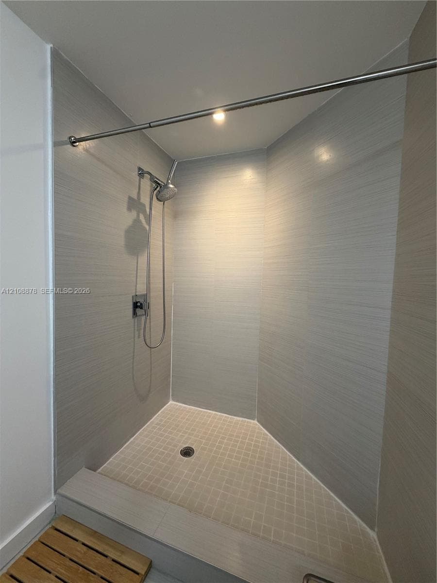 Floor-to-ceiling windows, wood-finish tile flooring, and a sliding glass door opening to a private balcony with metal railings