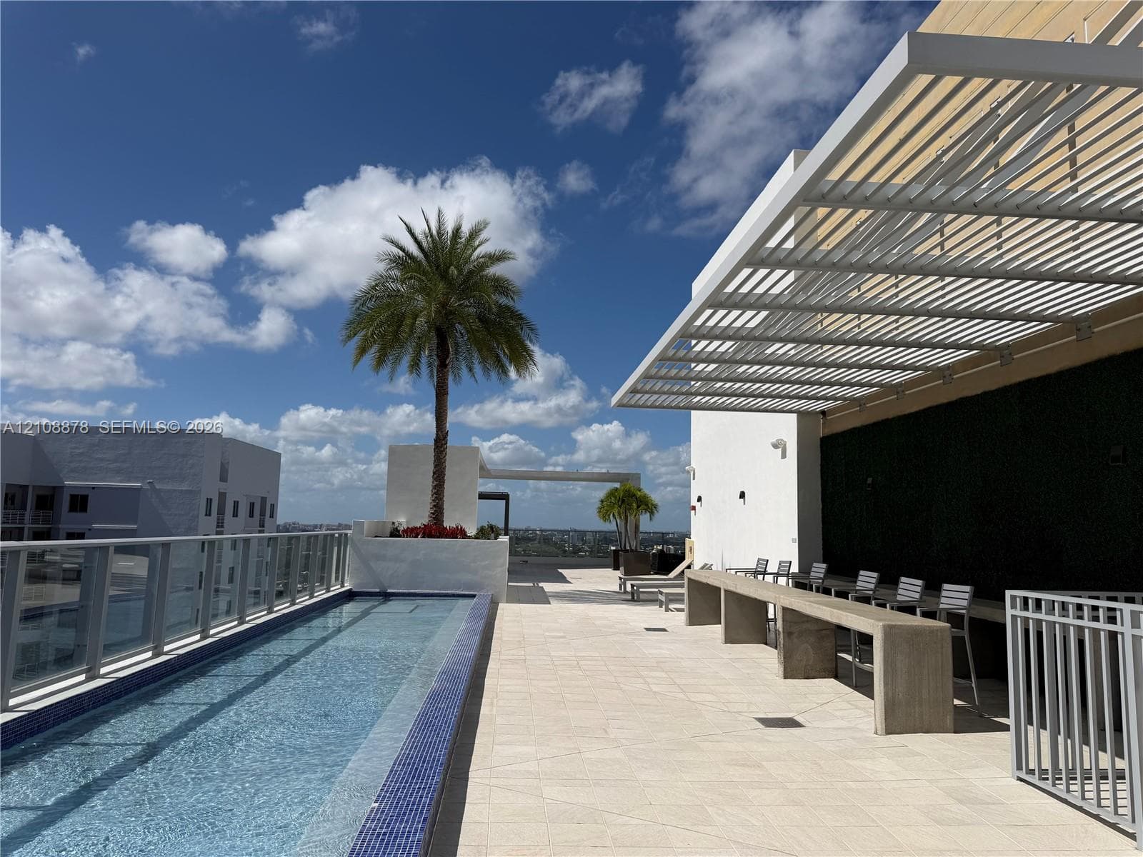 Outdoor spa featuring blue mosaic tile surround, built-in water feature, and stainless steel handrail set on a stone tile terrace