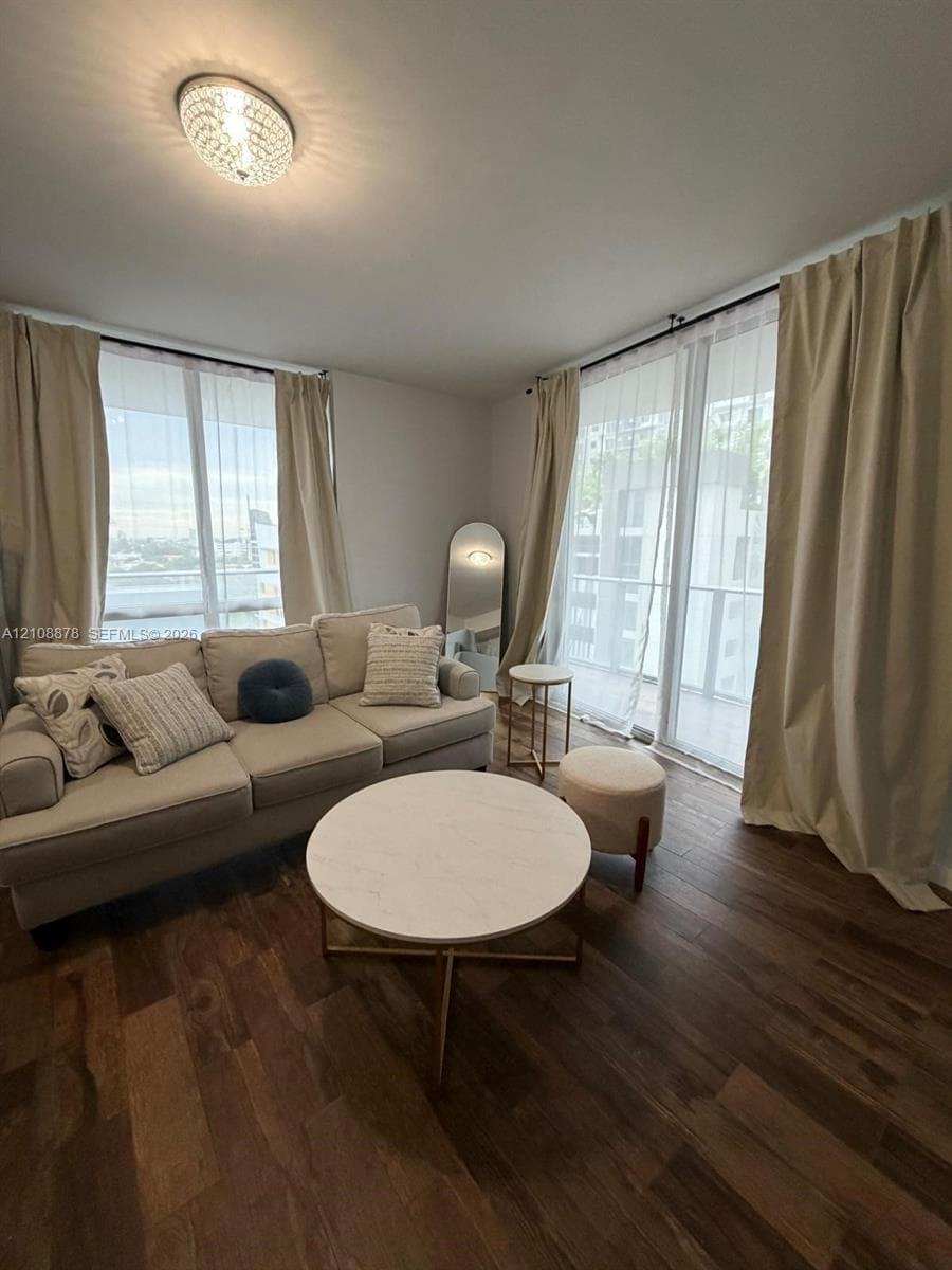 Living area featuring wood-finish flooring, dual floor-to-ceiling windows, and recessed ceiling ligh