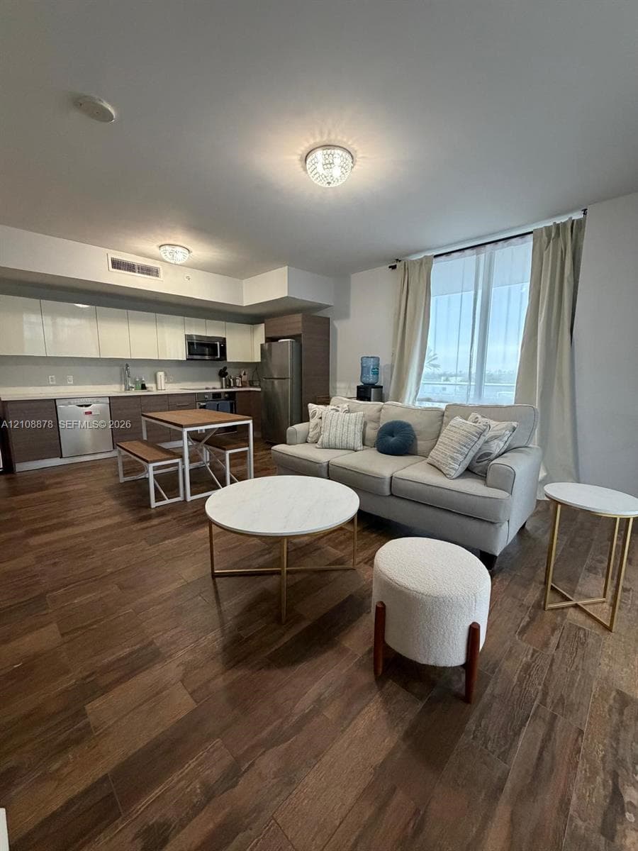 Contemporary kitchen featuring dual-tone cabinetry, stainless steel appliances, solid surface countertops, and wood-finish flooring