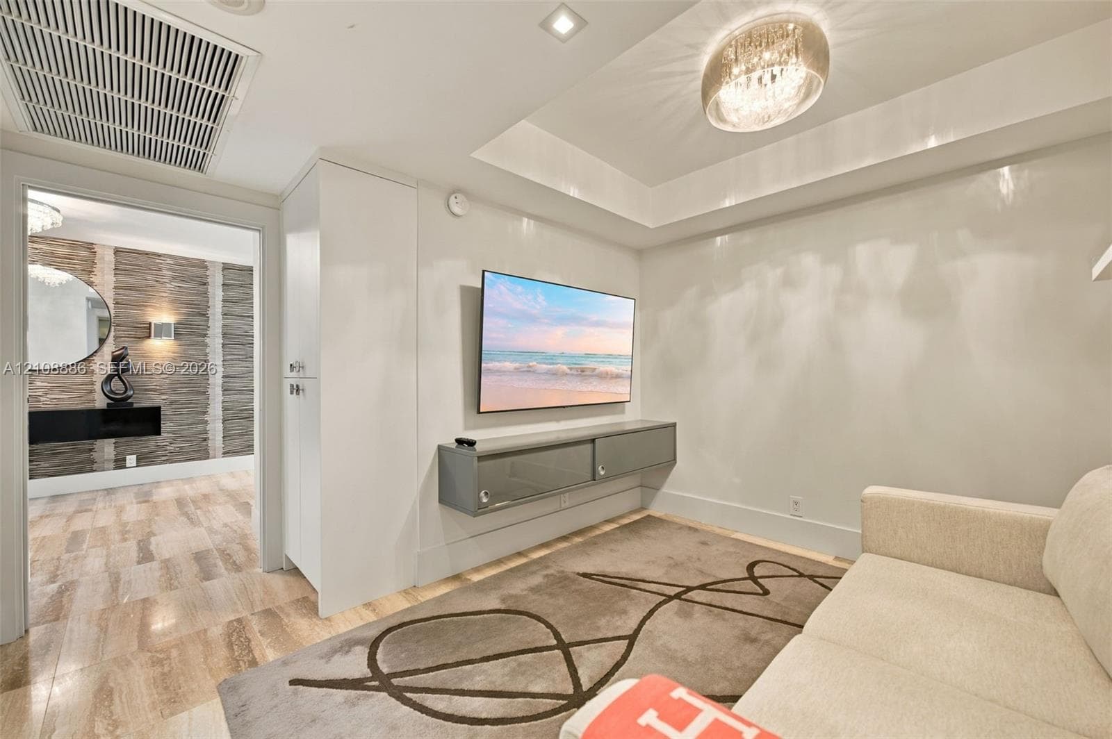 Interior room featuring a tray ceiling with a polished metallic flush-mount light fixture, custom floor-to-ceiling cabinetry, and a wall-mounted floating media console