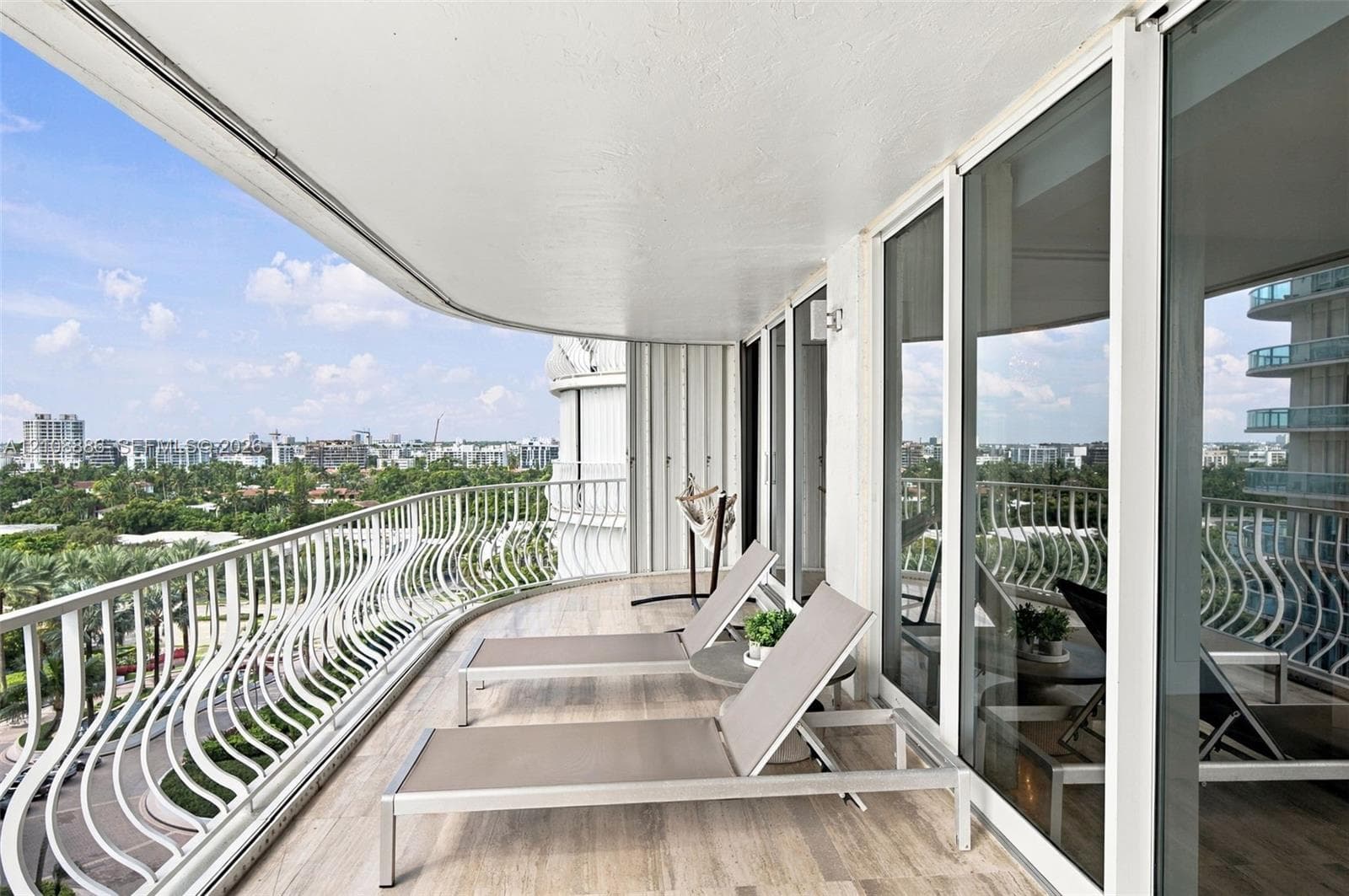 Curved balcony featuring tile flooring, white metal balustrades, and floor-to-ceiling glass sliding doors