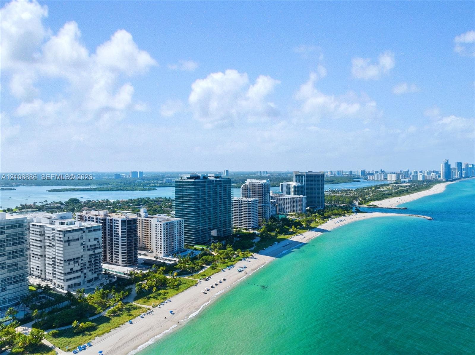 Aerial perspective of high-rise residential structures situated along a sand beach, coastal shoreline, and ocean