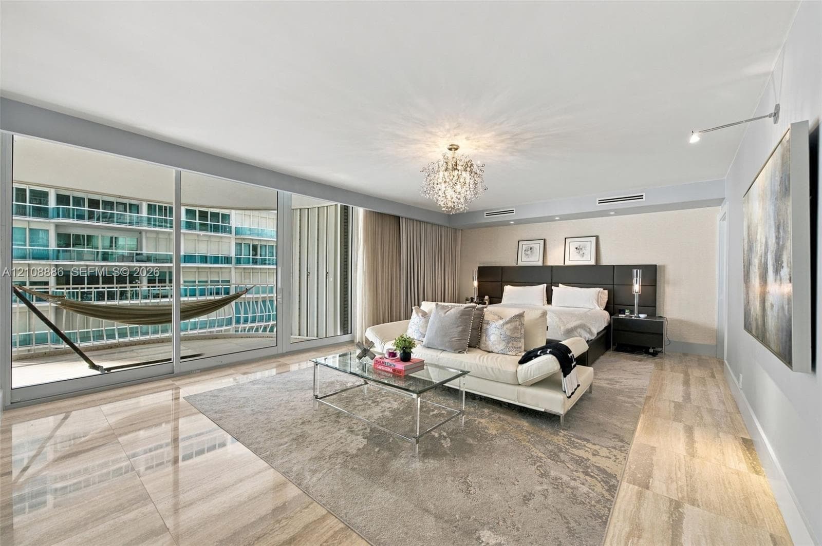 Floor-to-ceiling sliding glass doors, large-format stone tile flooring, built-in recessed ceiling lighting, multi-tiered crystal chandelier, and integrated wall-mounted accent lighting