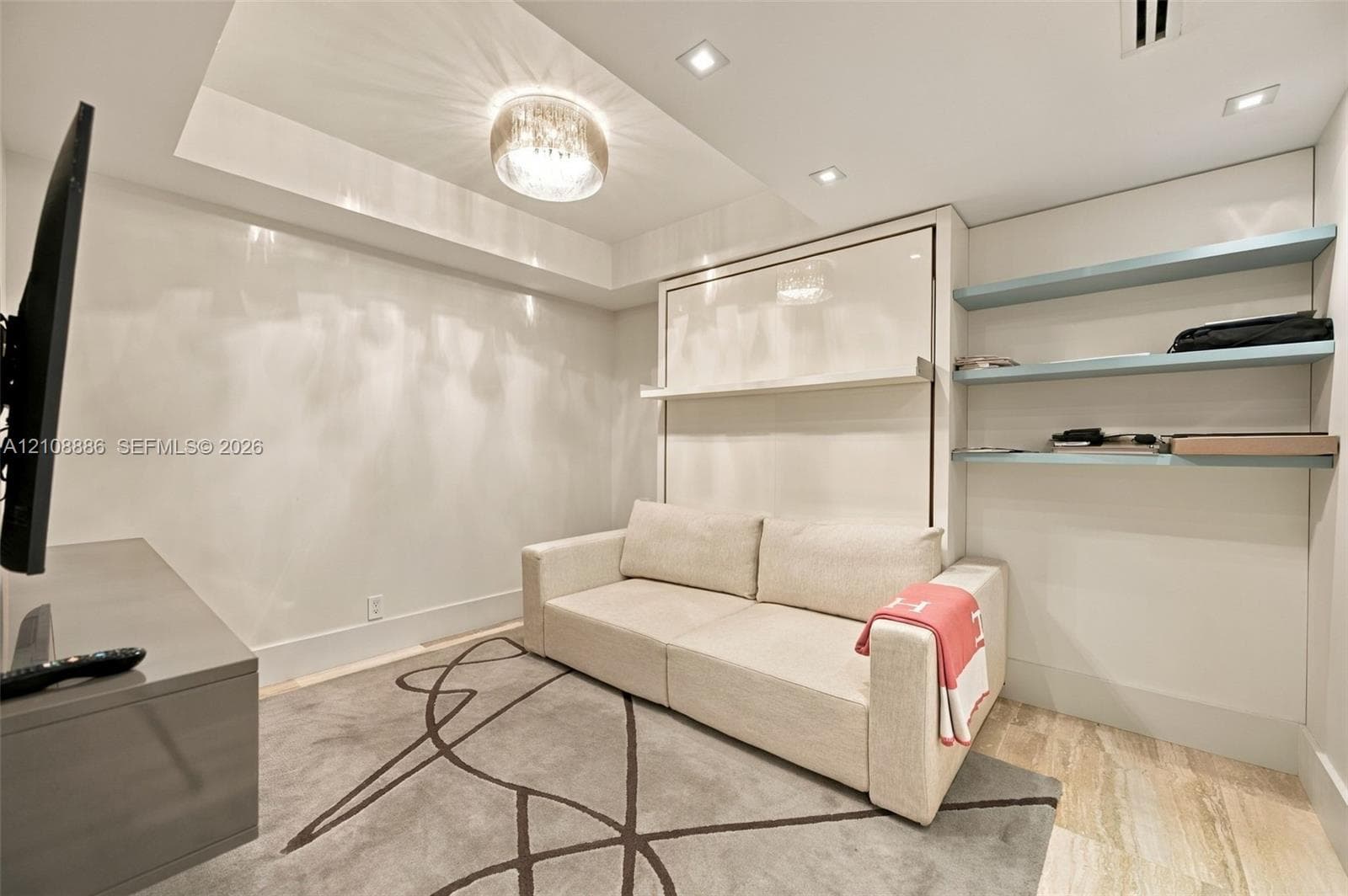 Built-in wall unit with integrated murphy bed system, recessed tray ceiling, custom built-in shelving, flush-mount lighting, and stone flooring