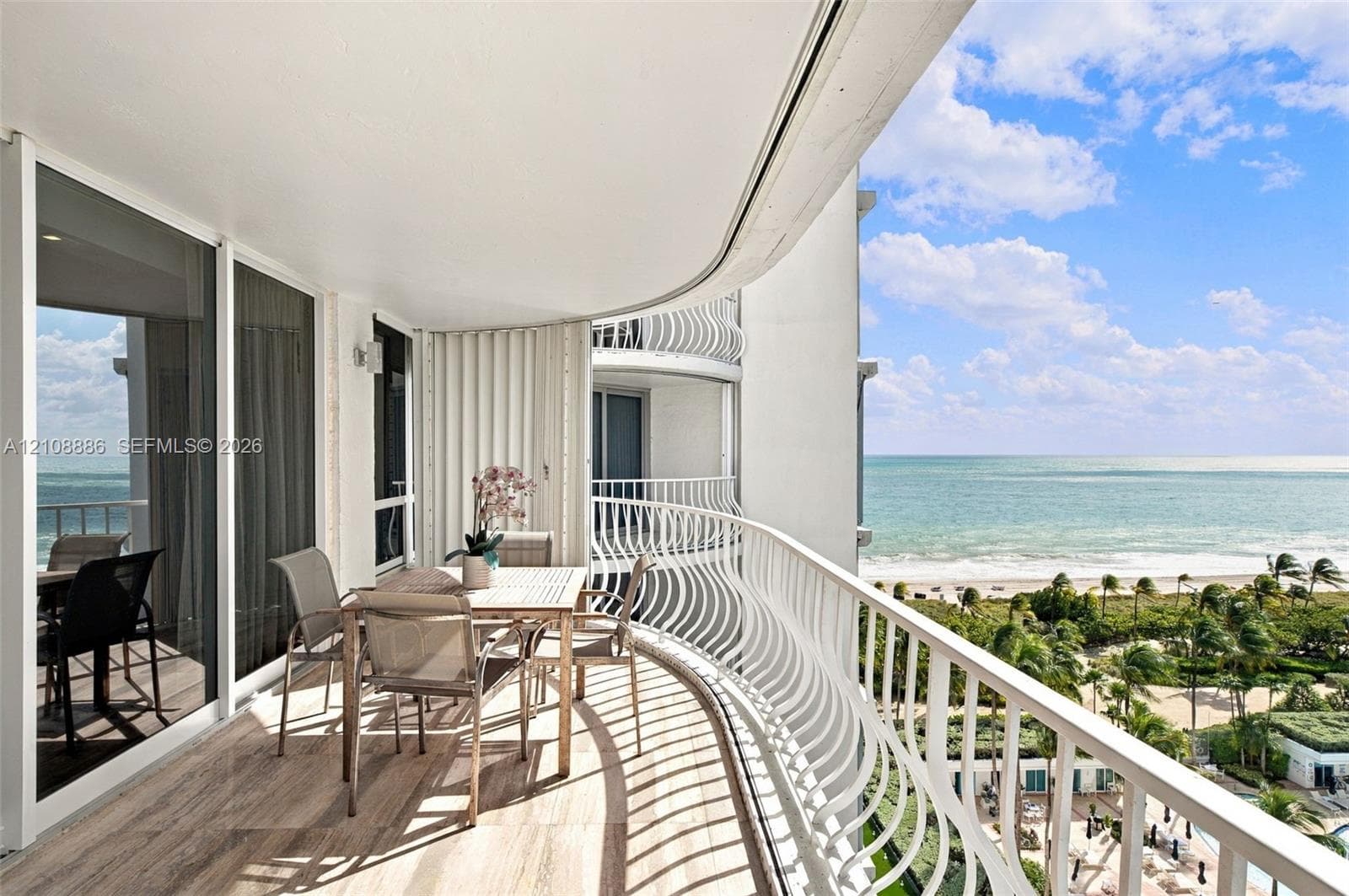 Expansive curved balcony featuring tile flooring, white metal railings, and floor-to-ceiling glass sliding doors
