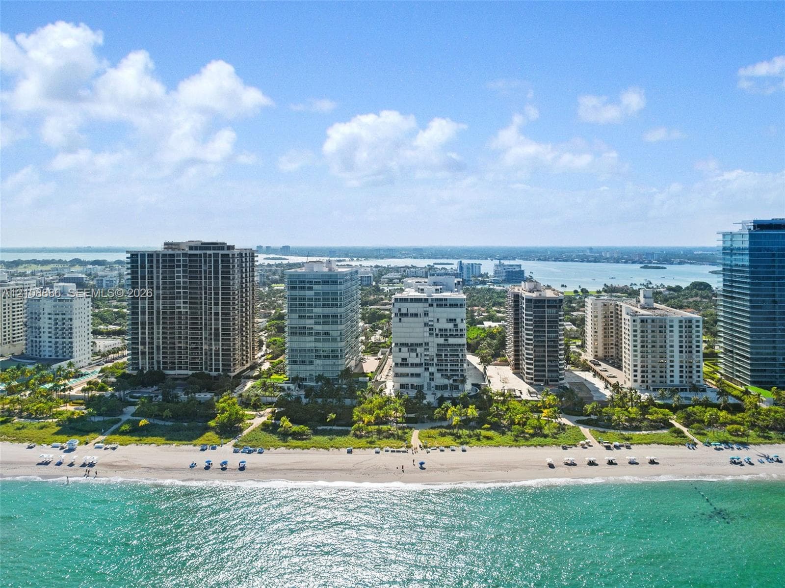 Aerial perspective featuring direct oceanfront access, pristine sandy shoreline, and multi-story high-rise architecture