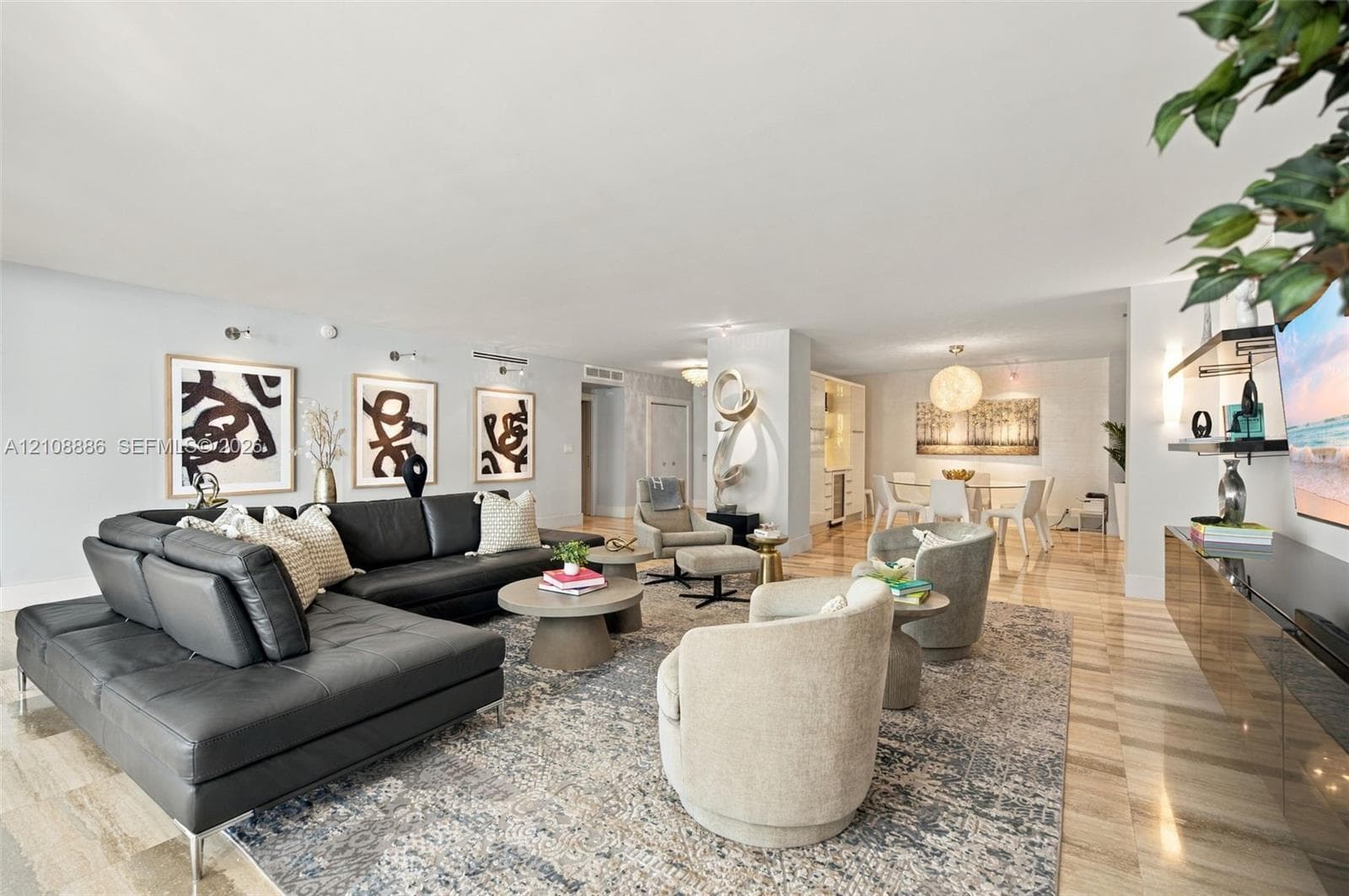 Open-concept interior featuring light-toned stone flooring, recessed ceiling lighting, wall-mounted adjustable sconces, and built-in cabinetry