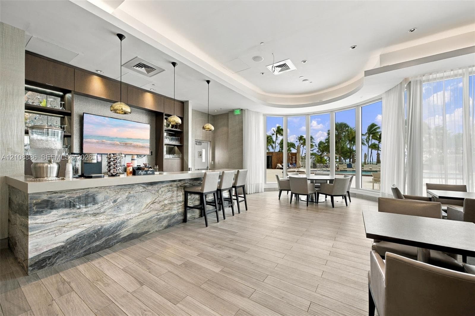 Entertainment bar featuring natural stone surfacing, wood-finish flooring, custom built-in cabinetry, metallic pendant lighting, and floor-to-ceiling panoramic windows