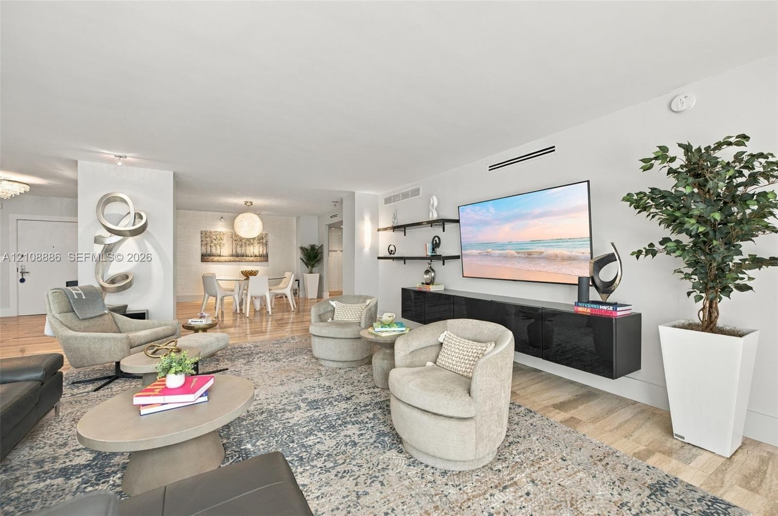 Open-concept living area featuring wood-finish flooring, a wall-mounted floating media console, and built-in wall shelving
