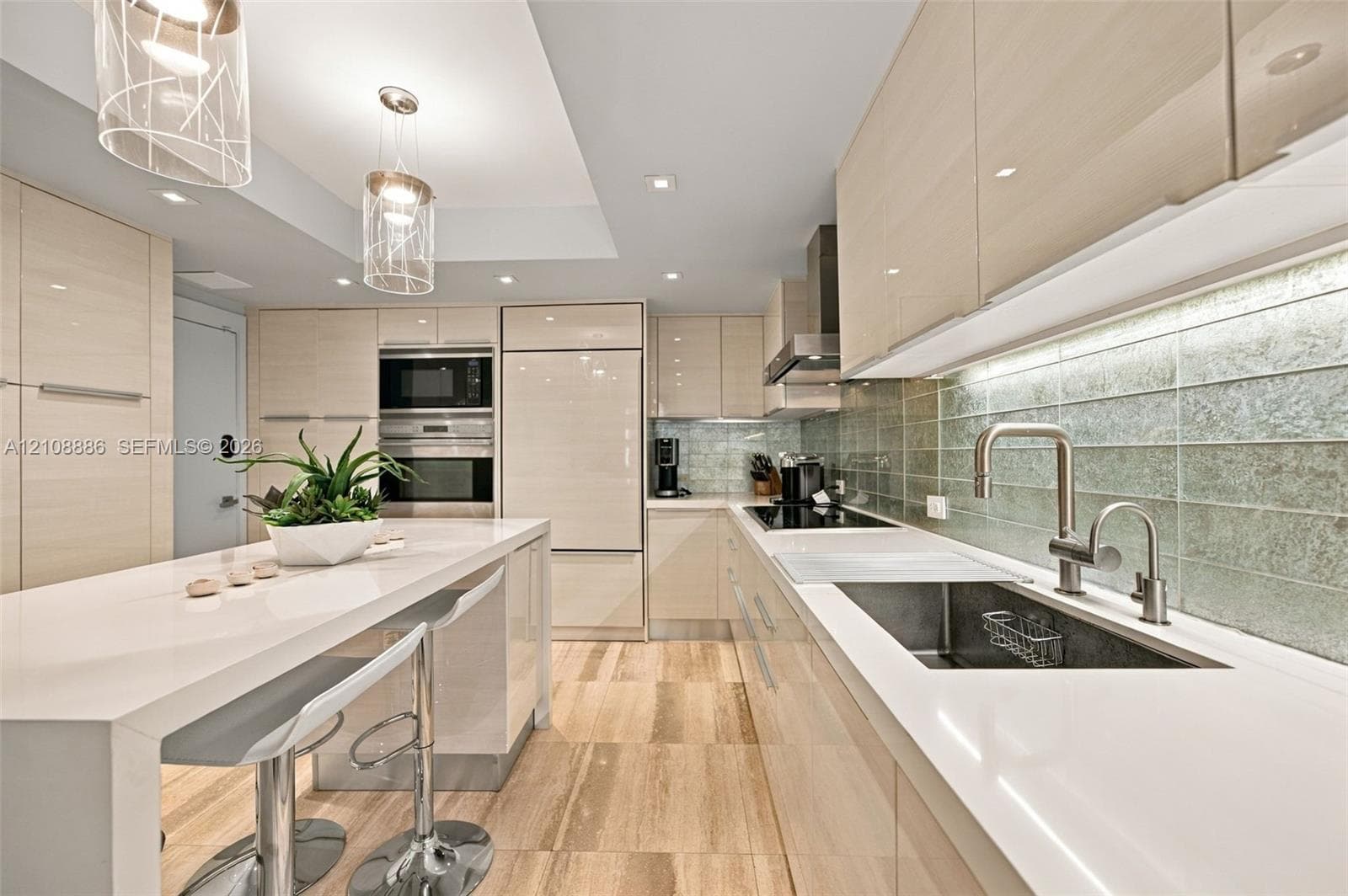 Modern kitchen featuring high-gloss cabinetry, stone countertops with an integrated breakfast bar, textured glass tile backsplash, stone flooring, and built-in stainless steel appliances