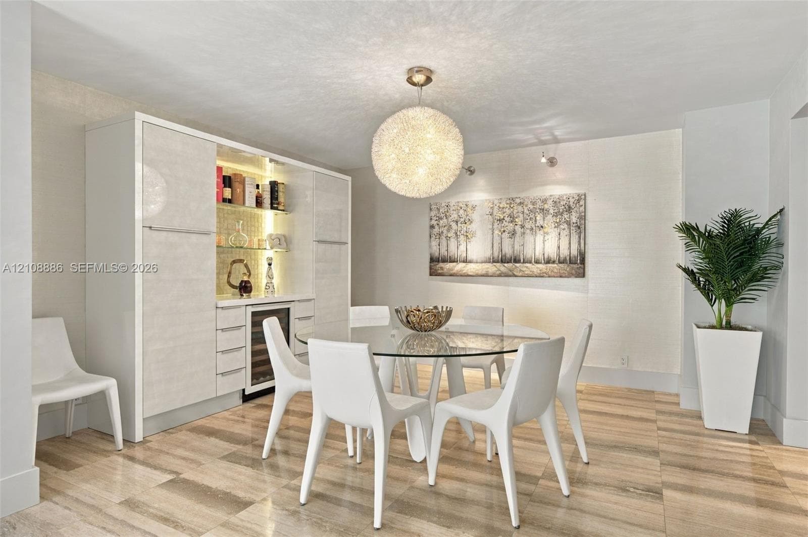 Built-in high-gloss cabinetry featuring an integrated wine refrigerator, glass shelving, and LED accent lighting, complemented by large-format neutral-toned tile flooring and a statement spherical pendant fixture