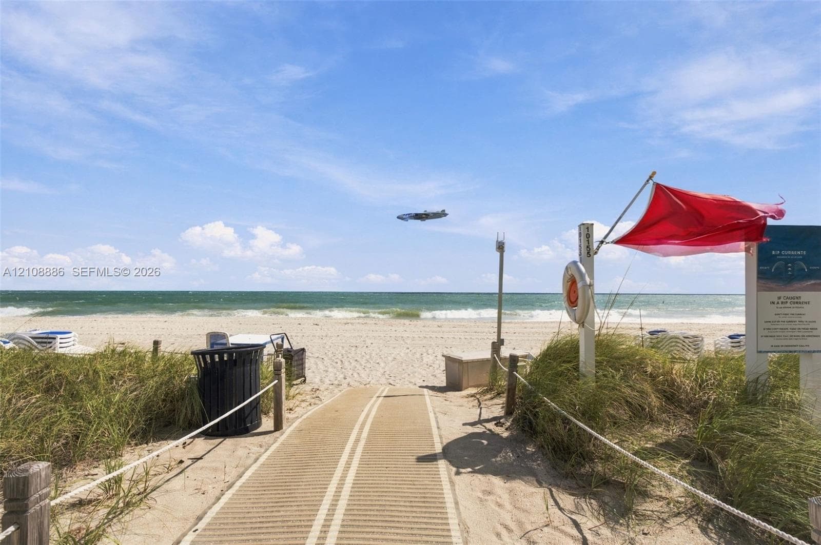 Direct beach access featuring a paved walkway, sand dunes, and rope-lined pathways