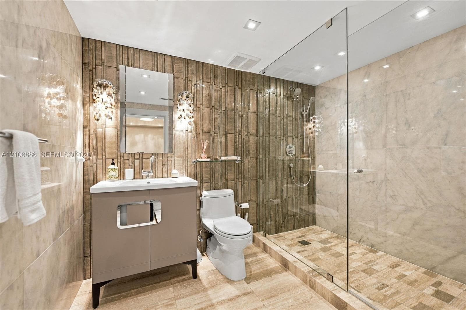 Bathroom featuring floor-to-ceiling stone-tiled walls, walk-in shower with glass partition, custom vanity, and recessed lighting