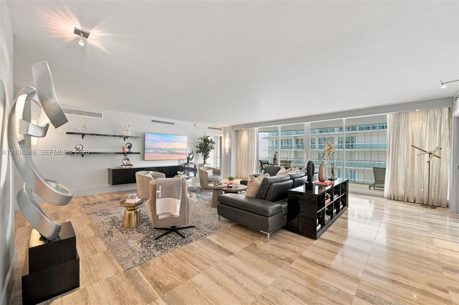 Open-concept interior featuring large-format natural stone flooring, floor-to-ceiling glass paneling, floating wall-mounted shelving, and built-in linear cabinetry
