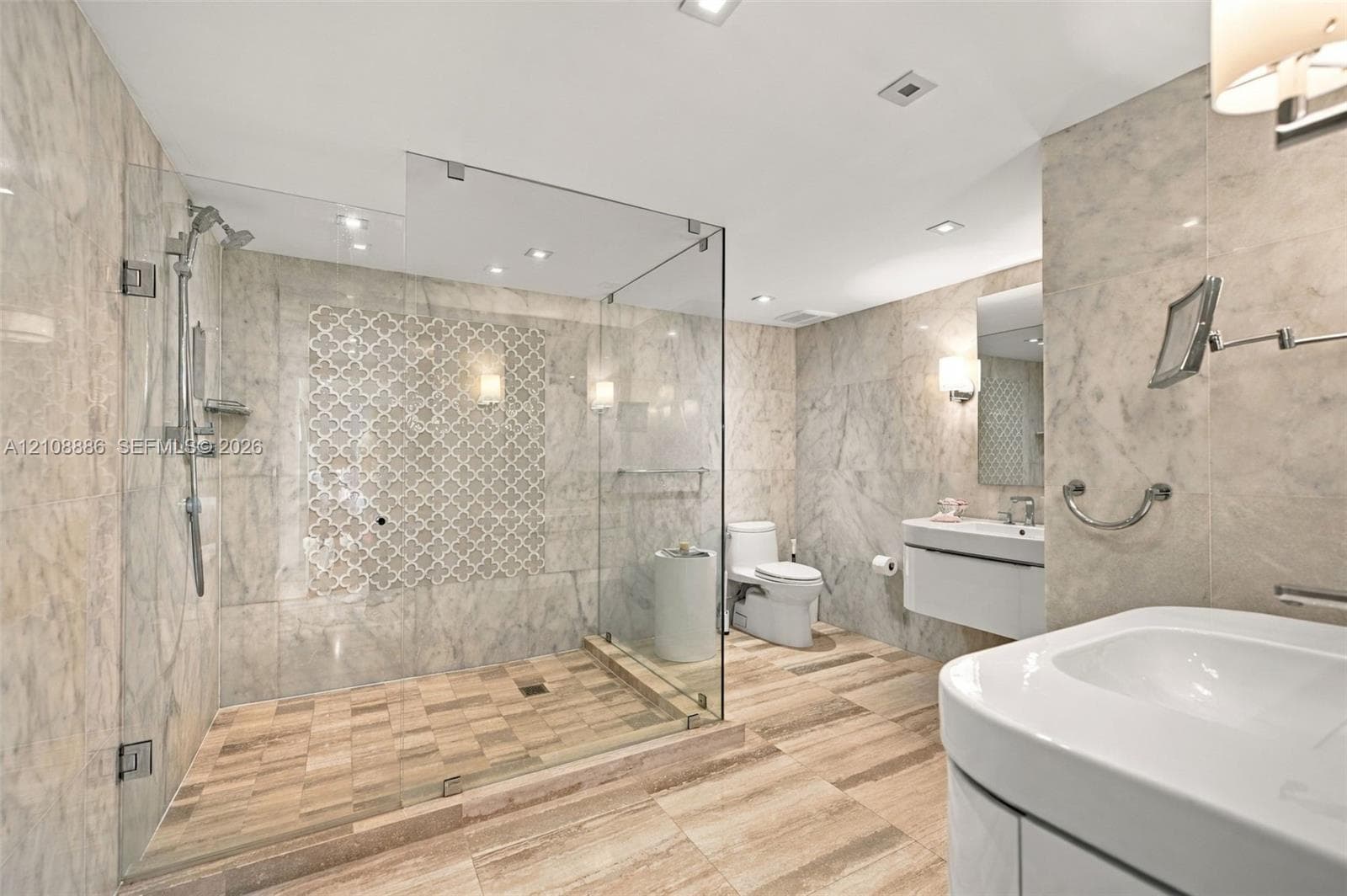 Bathroom featuring floor-to-ceiling stone wall tiling, a walk-in glass shower enclosure with decorative tile inlay, wood-finish flooring, a wall-mounted floating vanity, and recessed lighting