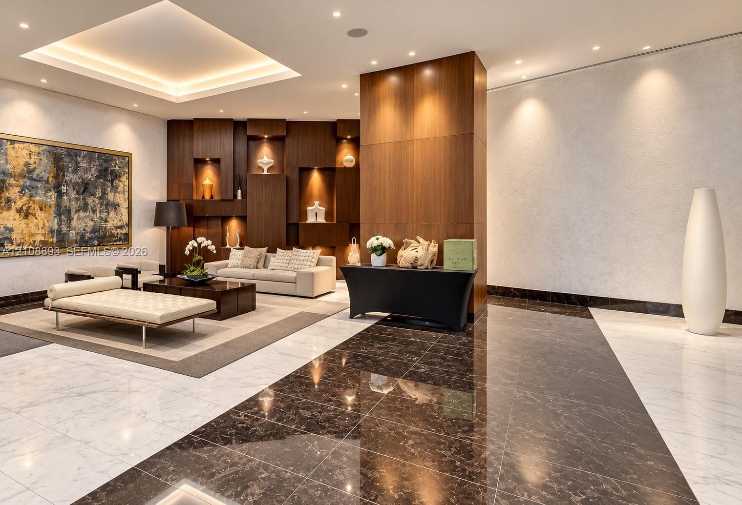 Polished stone flooring with contrasting inlay patterns, tray ceiling with recessed lighting, and wood-paneled accent wall featuring integrated display niches