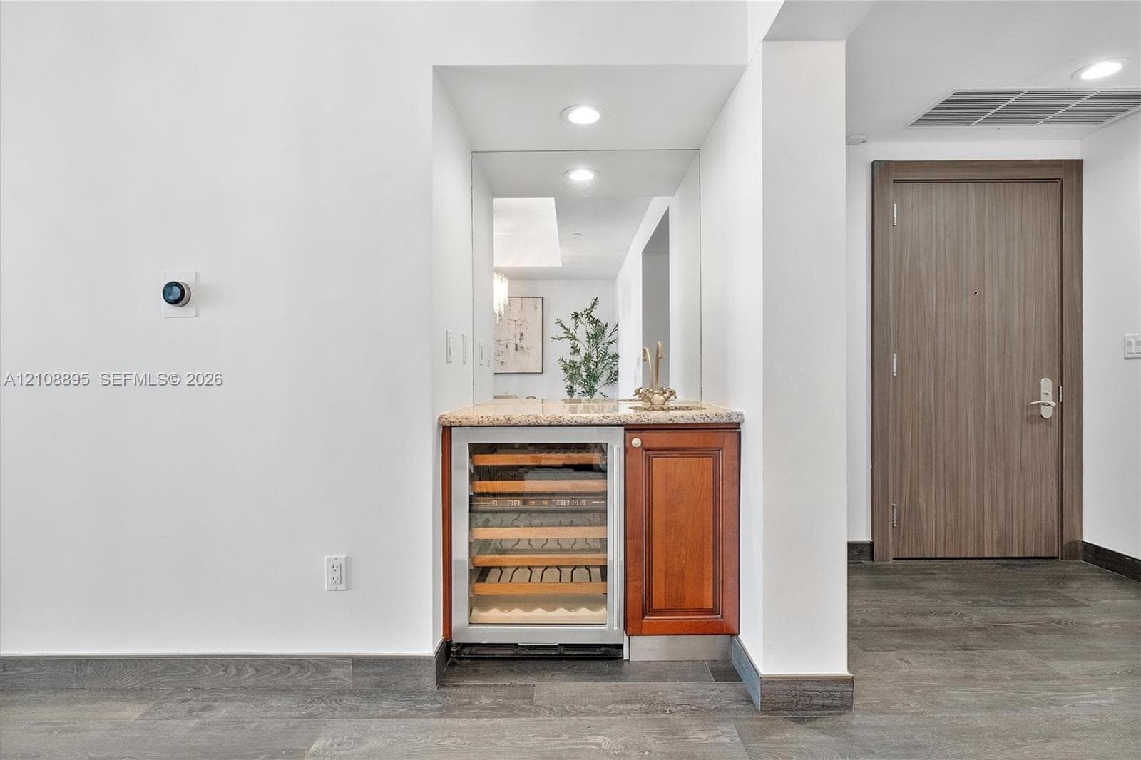 Built-in wet bar featuring a stone-topped counter, undermount sink, integrated wine refrigerator, and wood cabinetry