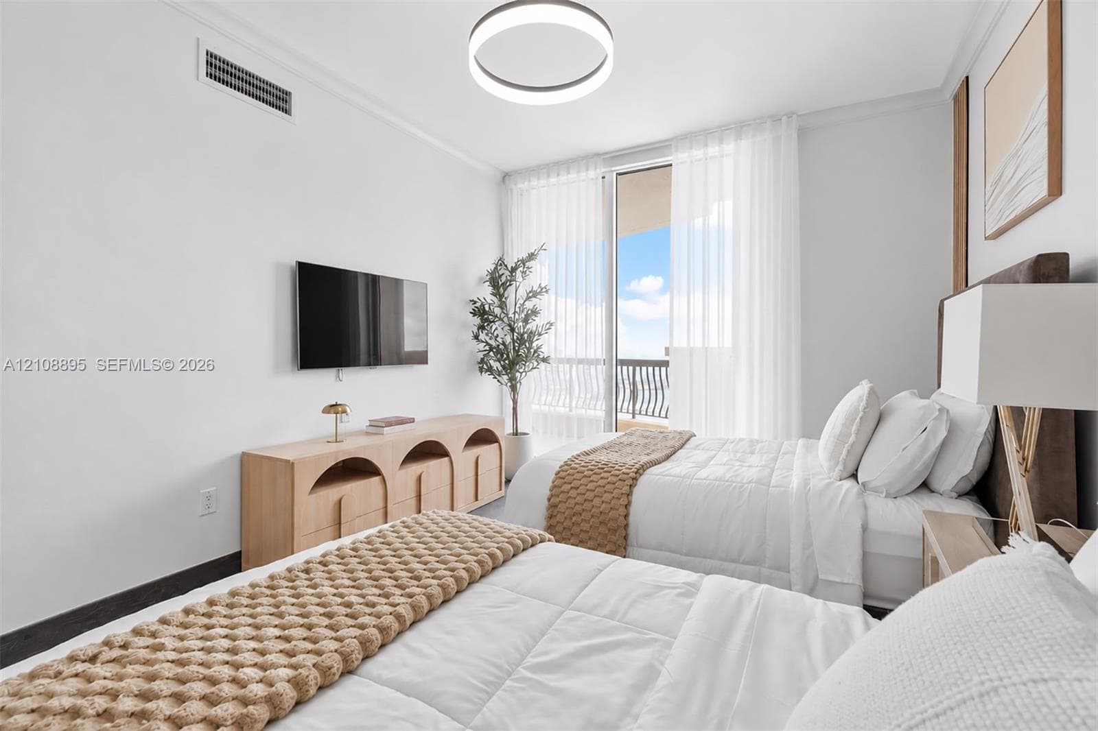 Bedroom featuring floor-to-ceiling glass sliding doors, private balcony access, modern circular LED ceiling fixture, and neutral wall finishes