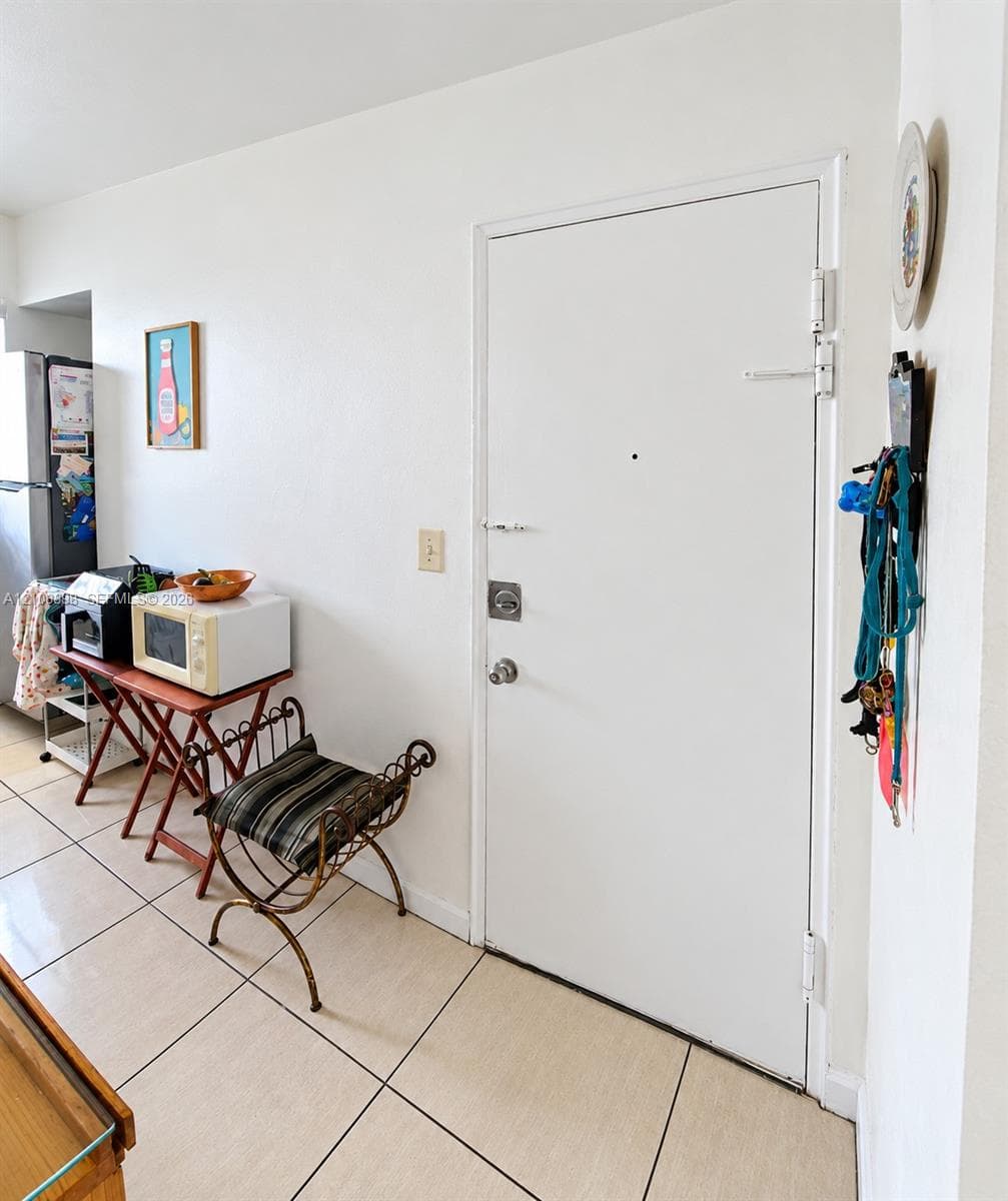 Neutral-tone tile flooring and a solid-panel door equipped with a security deadbolt and peephole