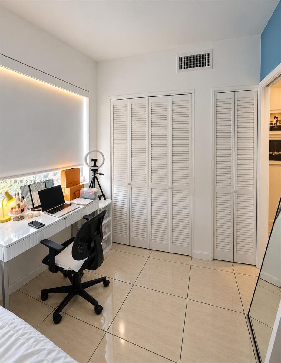 Large-format tile flooring, recessed cove lighting, and multiple louvered-door closets