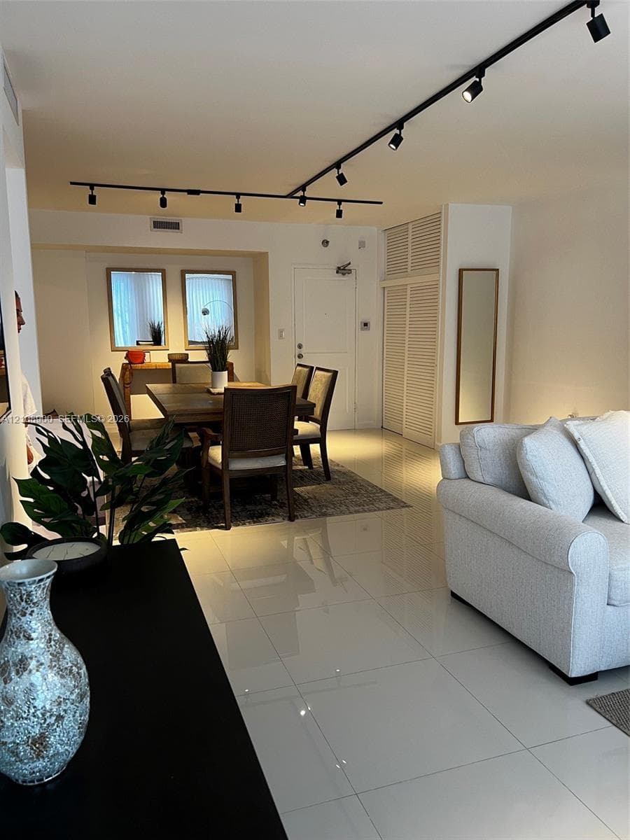 Large-format tile flooring, adjustable overhead track lighting, and louvered-panel built-in closet doors
