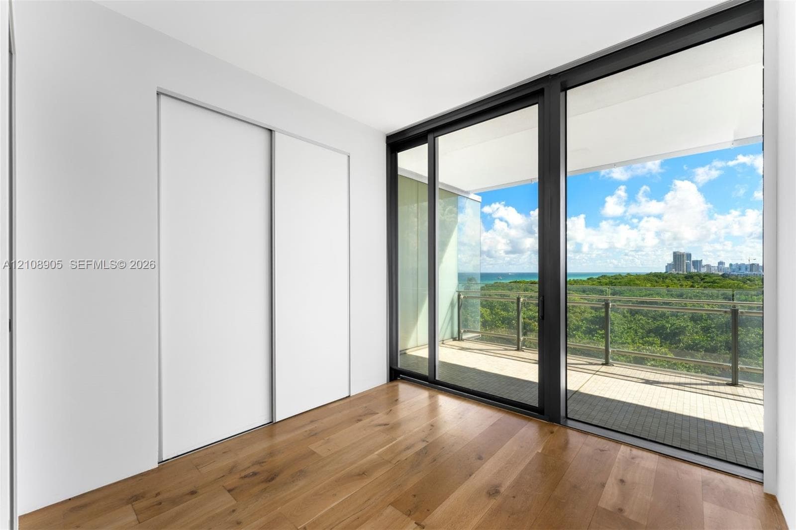 Floor-to-ceiling glass sliding doors, private balcony, wood-finish flooring, and built-in sliding door closet