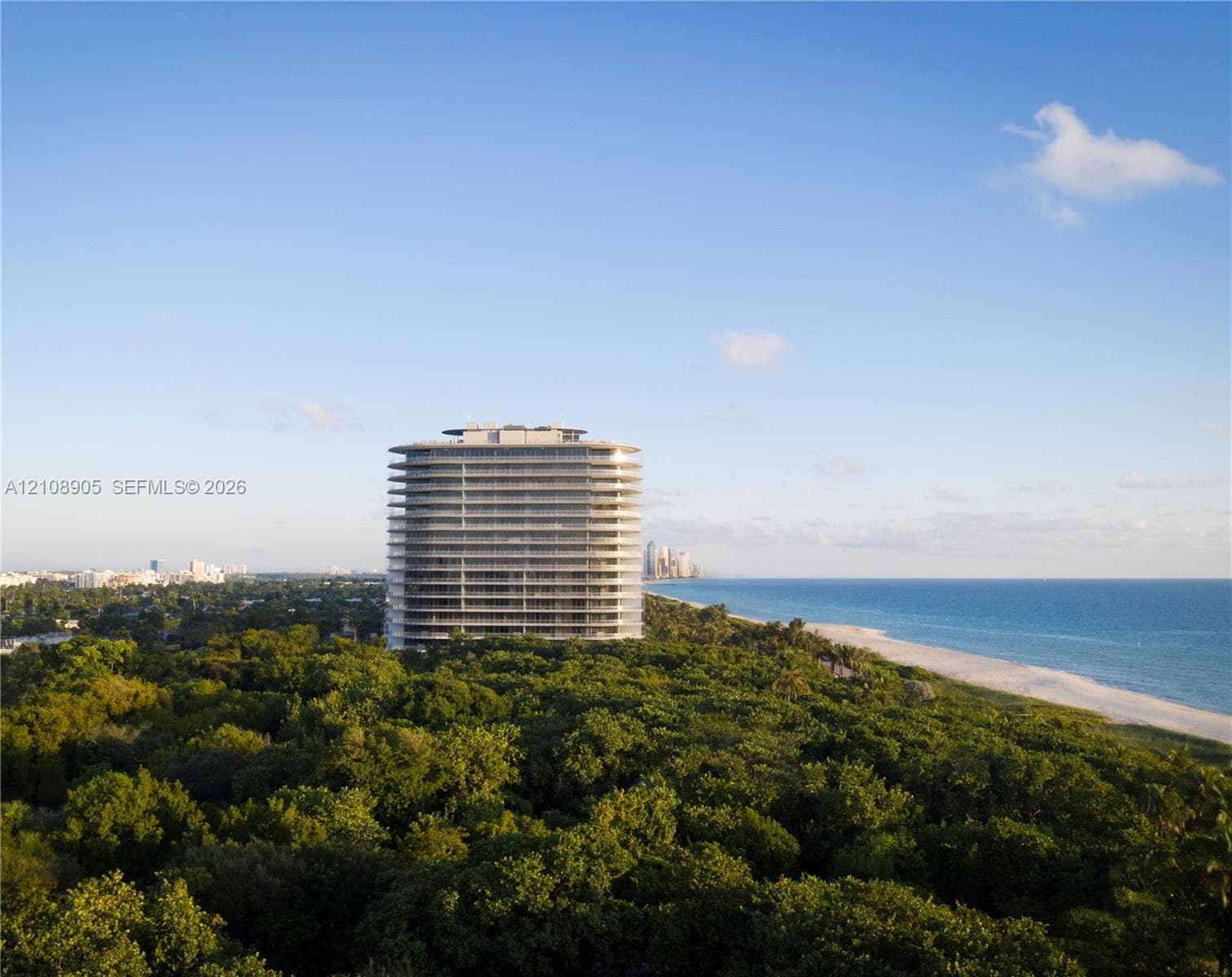 High-rise residential building featuring wraparound balconies, floor-to-ceiling glass paneling, and direct coastal proximity