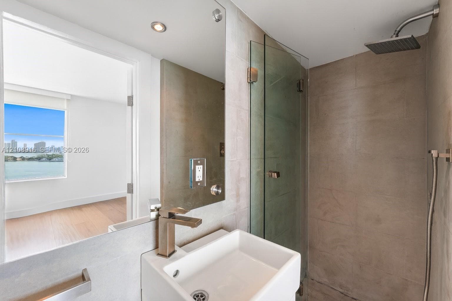 Private bathroom connected to secondary bedroom featuring rainfall shower head as well as convenient handheld shower and natural limestone finishes