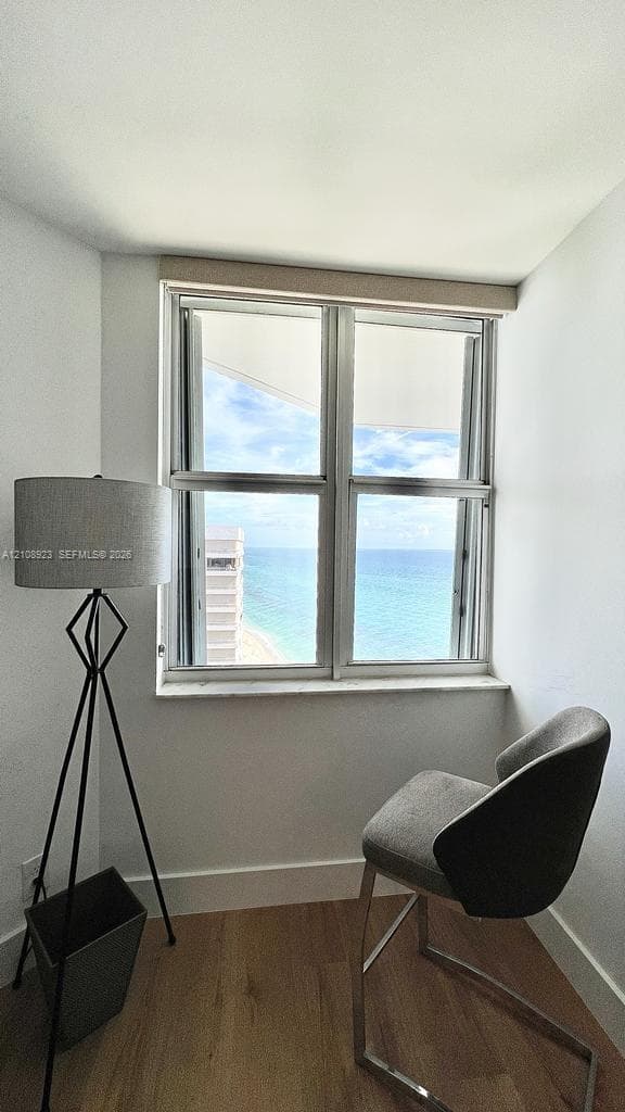 Double-pane sliding window with neutral trim, wood-finish flooring, and coastal scenery