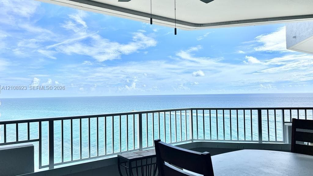 Covered balcony with white metal railings and ocean backdrop