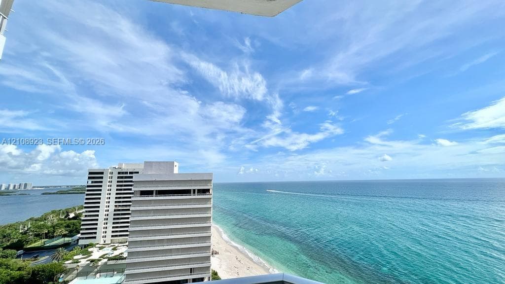 Elevated balcony featuring expansive coastal, ocean, and sandy shoreline scenery