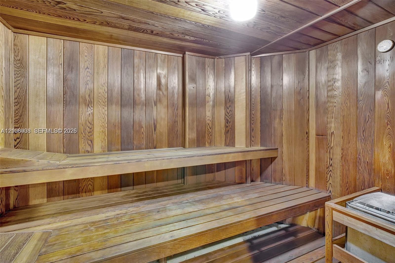 Sauna featuring tongue-and-groove wood paneling, multi-level slatted benches, and a built-in heating unit