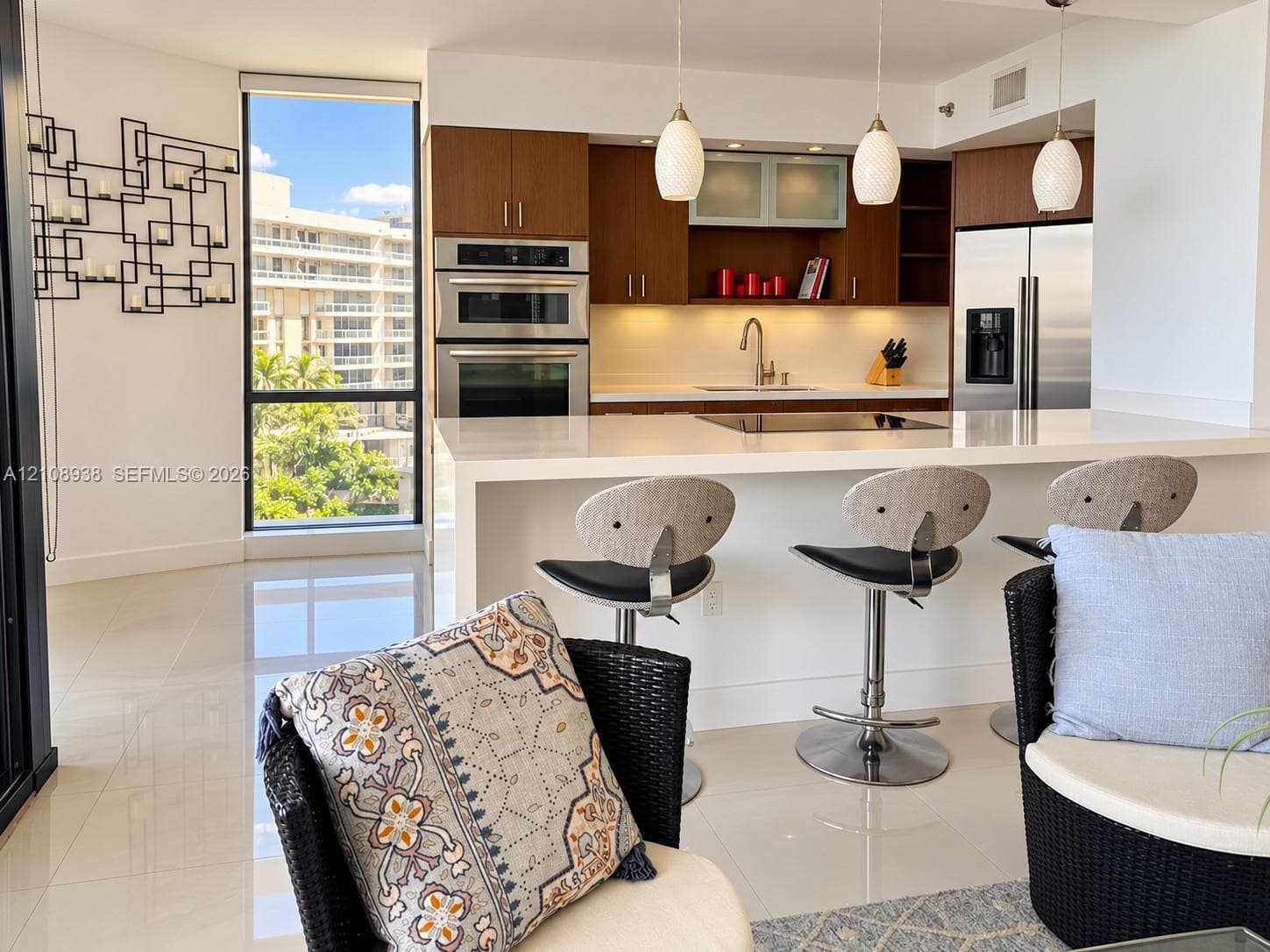 Contemporary kitchen featuring wood-finish cabinetry, a white waterfall-edge island, built-in stainless steel appliances, and glass pendant lighting