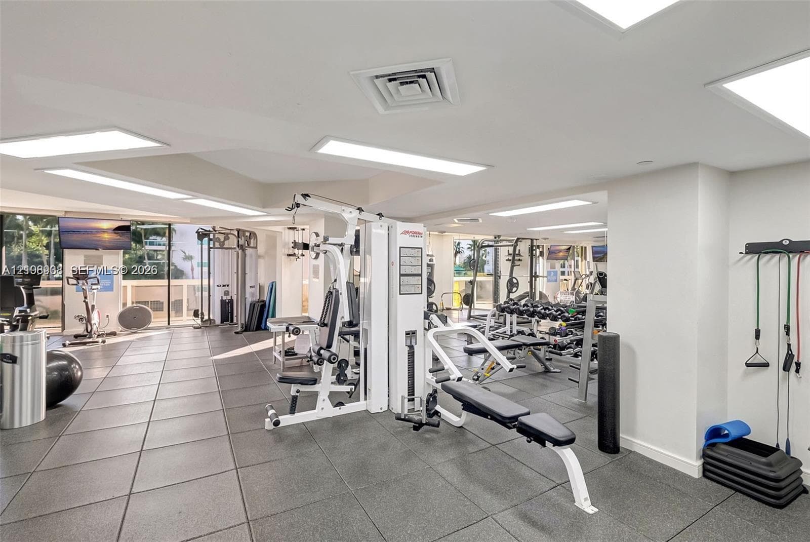 Fitness center featuring large-format tile flooring, recessed panel lighting, and floor-to-ceiling windows