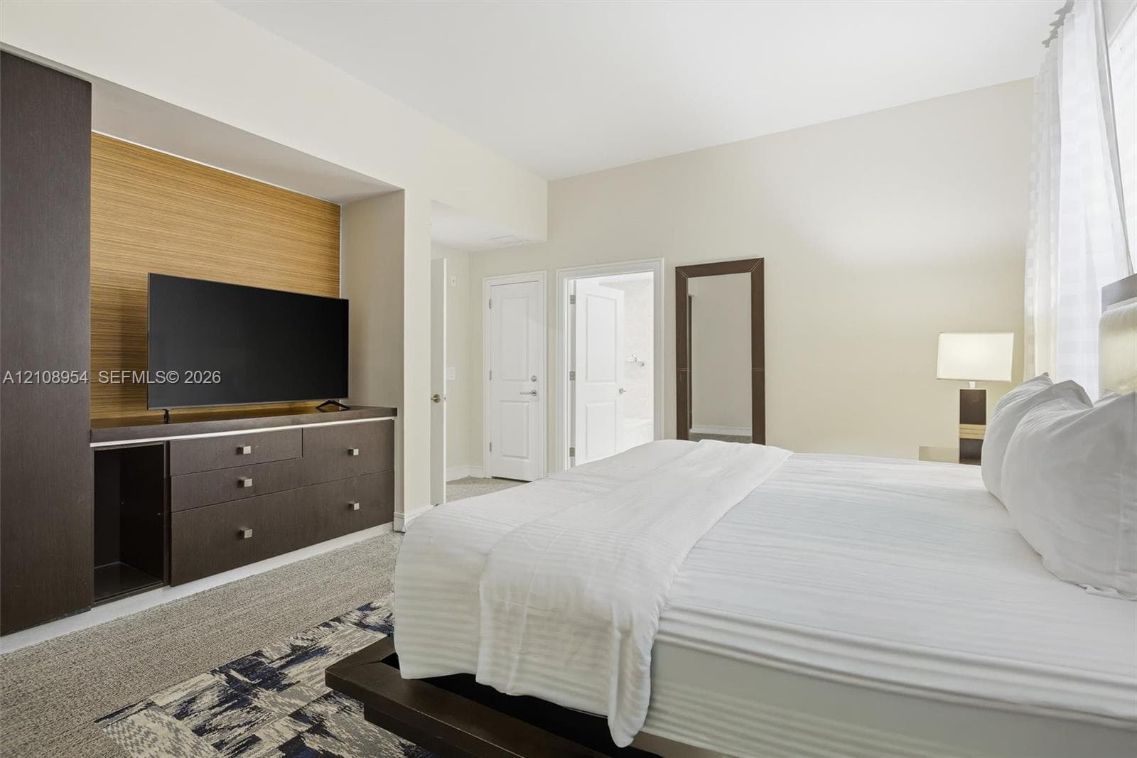 Built-in wall cabinetry with a wood-accented media niche, multi-drawer storage, two interior passage doors, and neutral wall-to-wall carpeting