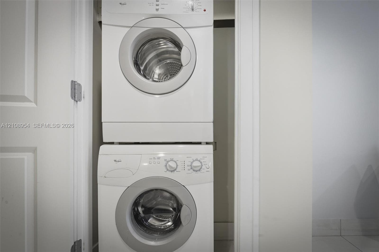 Stacked white front-loading washer and dryer unit housed within a dedicated closet
