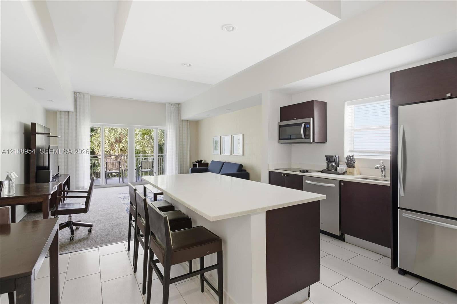 Kitchen featuring a central island with a solid surface countertop, dark-finish cabinetry, stainless steel appliances, recessed ceiling lighting, and tile flooring