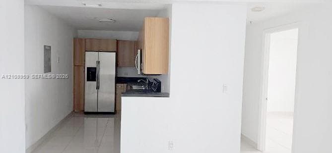 Kitchen featuring light wood-finish cabinetry, stainless steel refrigerator, stone-finish countertops, and tile flooring