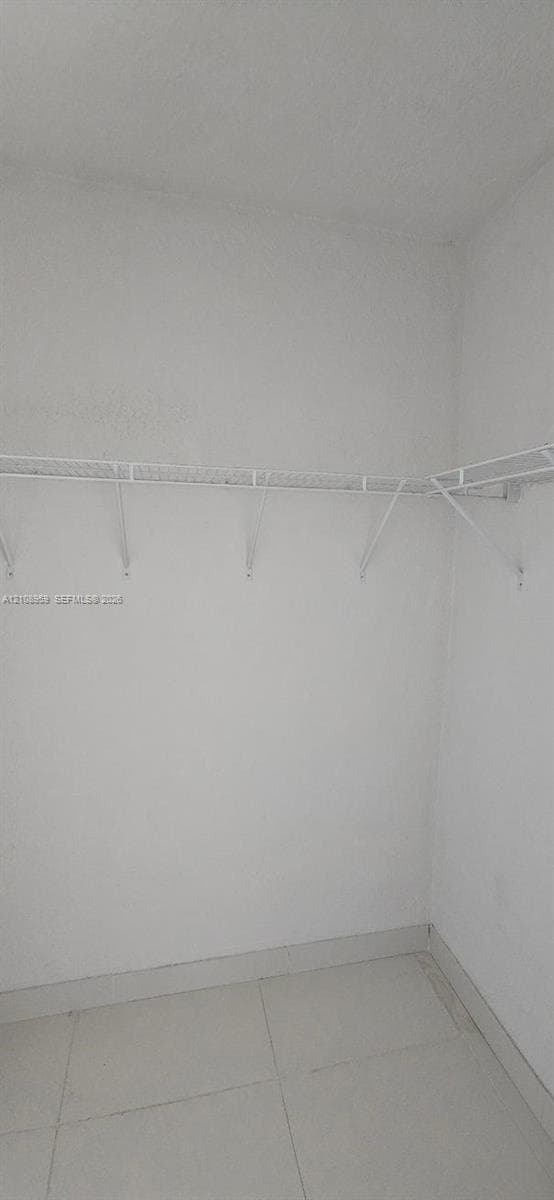 Closet featuring white wall-mounted wire shelving and neutral tile flooring