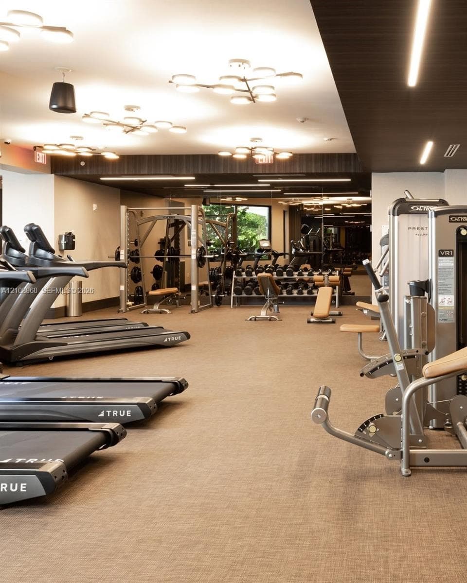Fitness center featuring multiple treadmills, resistance training equipment, free weights, textile flooring, and decorative flush-mount lighting fixtures