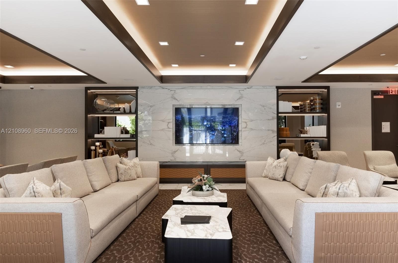 Tray ceiling with recessed lighting, integrated stone-finish media wall, and built-in display cabinetry with accent lighting