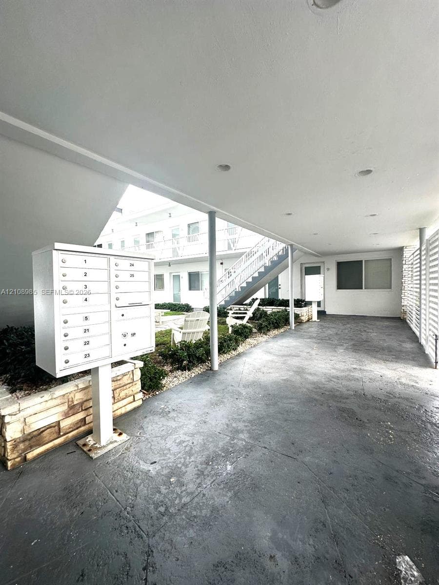 Covered exterior breezeway with recessed lighting, integrated metal parcel delivery station, and a stone-accented landscape border