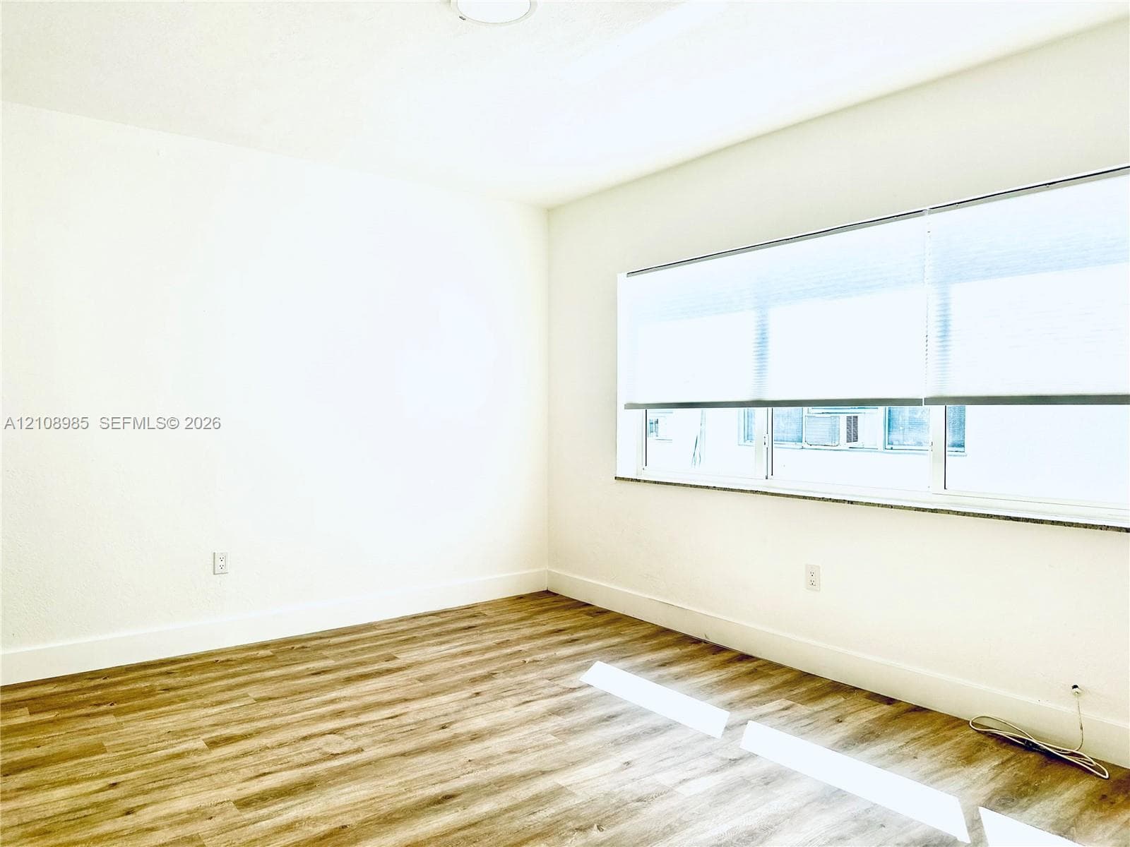 Wood-finish flooring and a large window featuring a stone sill