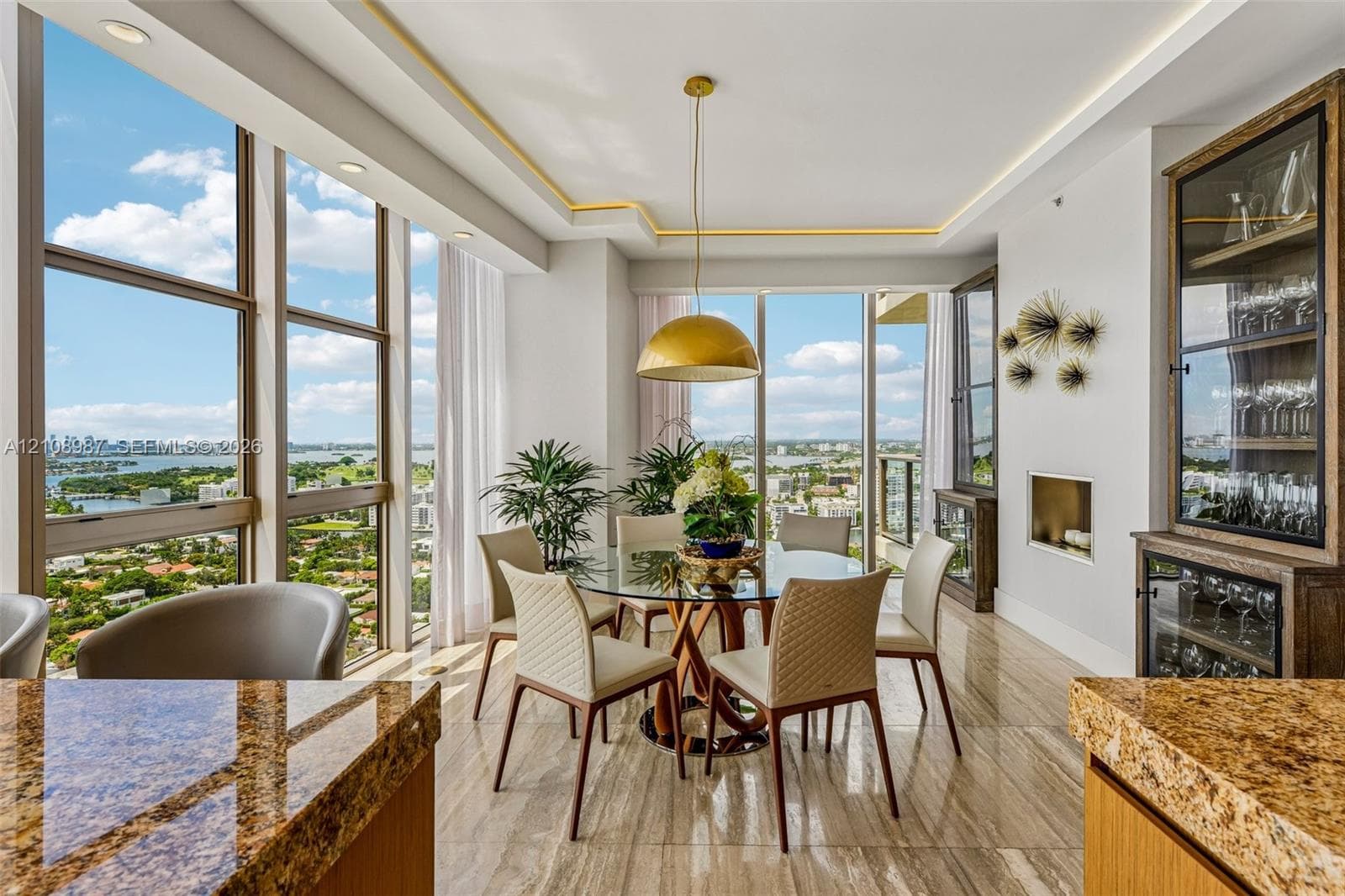 Floor-to-ceiling windows, stone tile flooring, built-in display cabinetry, tray ceiling with recessed lighting, and a recessed fireplace