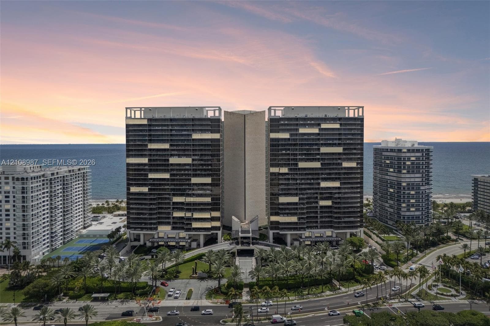 High-rise residential complex featuring a dual-tower structural design, expansive private balconies, ground-level landscaped courtyards, and direct coastal proximity