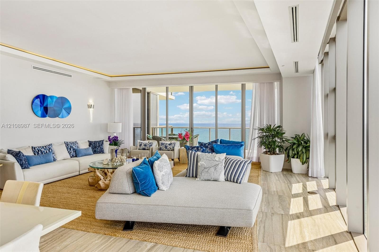 Floor-to-ceiling glass panel walls, natural stone flooring, recessed perimeter ceiling lighting, and expansive balcony access