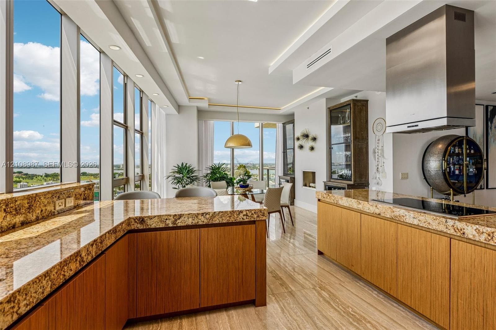 Kitchen featuring natural stone countertops, flat-panel wood cabinetry, floor-to-ceiling windows, stainless steel range hood, and tile flooring