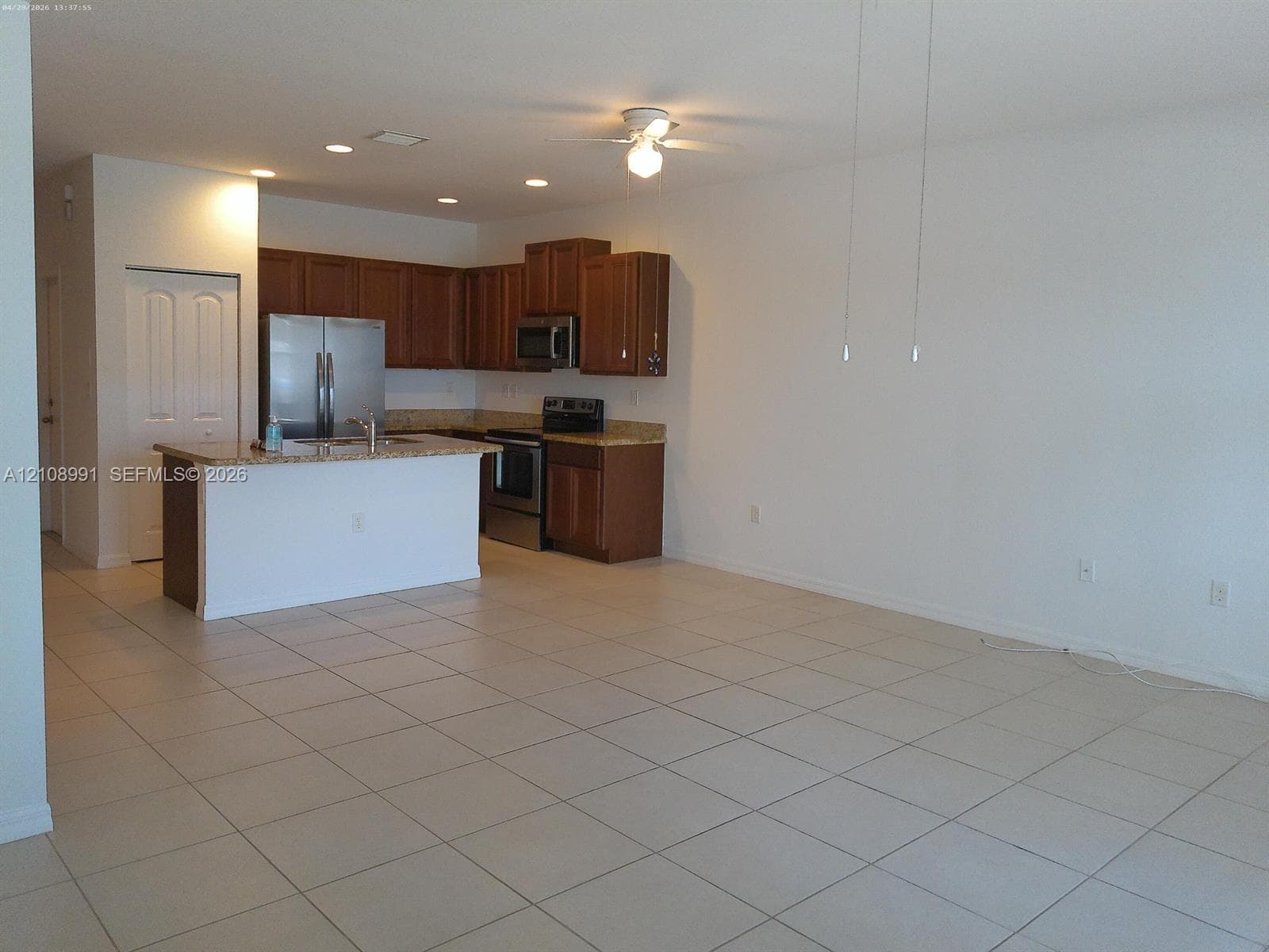 Kitchen featuring wood cabinetry, stone-finish countertops, stainless steel appliances, recessed ceiling lighting, and tile flooring